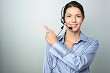 Smiling businesswoman with a headset pointing