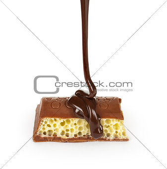 dark chocolate is poured onto a piece of porous chocolate on a w