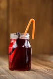 Cherry juice in jar with cocktail tube and vanilla