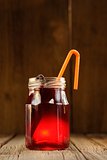 Cherry juice in jar with cocktail tube and vanilla