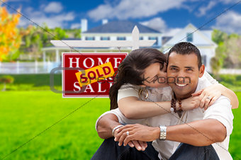 Hispanic Couple, New Home and Sold Real Estate Sign