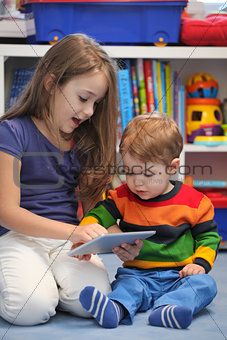 Girl with her little brother fun using a digital tablet computer