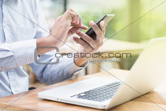 Businessman using smartphone and laptop computer 