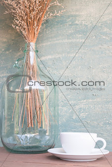 Coffee cup and dried flower vase on wooden table