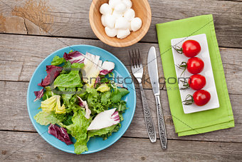 Fresh healthy salad, tomatoes, mozzarella on wooden table