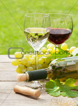 White and red wine glasses and bottle with bunch of grapes