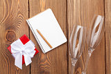 Blank notepad, valentines day gift box and two champagne glasses