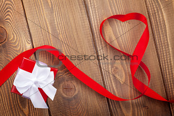 Heart shape ribbon and gift box over wood valentines day background