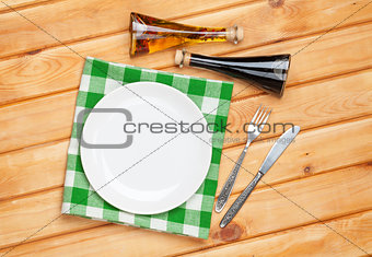 Empty plate, silverware and towel over wooden table background