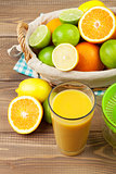 Citrus fruits in basket and glass of juice. Oranges, limes and lemons