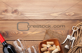 Red wine bottle, glasses, bowl with corks and corkscrew