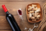 Red wine bottle, glass of wine, bowl with corks and corkscrew