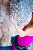 Cropped view of young woman climbing natural cliff, hand in focus