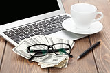 Office table with pc, coffee cup, glasses and money