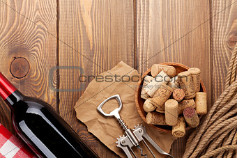 Red wine bottle, bowl with corks and corkscrew. View from above