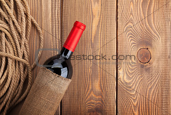 Red wine bottle over rustic wooden table background