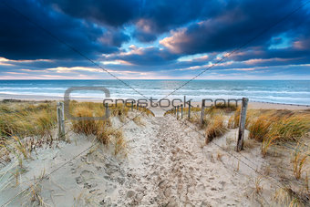 sand path to North sea coast at sunset