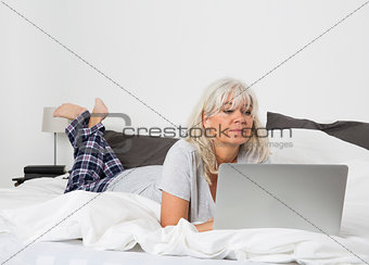 Mid Age woman with a laptop in bed