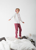 Little girl with Headphones jumping in bed