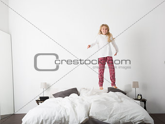 Happy little Girl jumping in bed