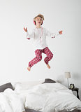 Little girl with headphones jumping in bed