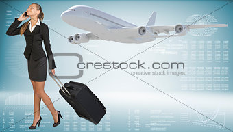 Businesswoman carrying suitcase while talking on the phone. Image of flying airliner beside