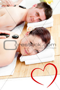 Composite image of cute young couple receiving a back massage with hot stones