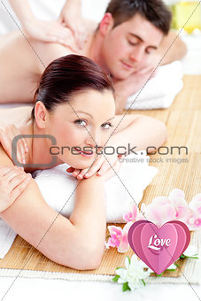 Composite image of relaxed young couple receiving a back massage