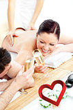 Composite image of loving young couple drinking champagne lying on a massage table