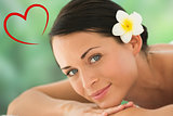 Composite image of beautiful brunette relaxing on massage table smiling at camera