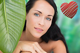 Composite image of beautiful nude brunette smiling at camera with green leaf