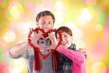 Composite image of couple making a heart shape
