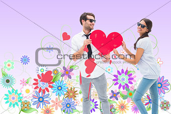 Composite image of hipster couple smiling at camera holding a heart