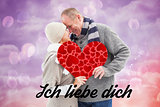 Composite image of happy mature couple in winter clothes holding red heart