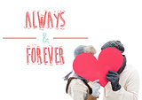 Composite image of attractive young couple in warm clothes holding red heart