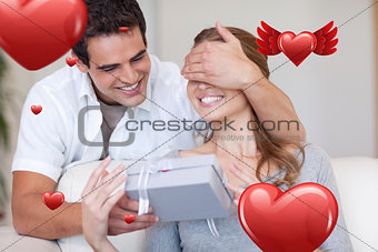 Composite image of man covering the eyes of his girlfriend while giving her a present