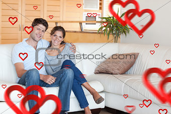 Composite image of couple sitting on a sofa