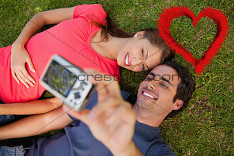 Composite image of man taking a photo with his friend while lying side by side