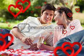 Composite image of man smiling as he looks at his friend during a picnic