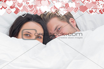 Composite image of couple hiding under the duvet
