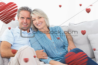 Composite image of cheerful couple on their couch