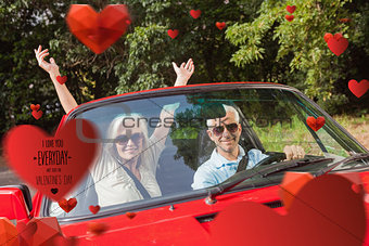 Composite image of mature couple in red cabriolet cheering at camera