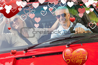 Composite image of happy mature couple in red cabriolet