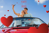 Composite image of cheerful couple standing in red cabriolet taking picture