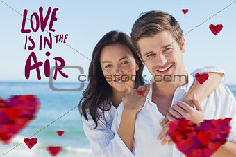 Composite image of cheerful couple embracing on the beach
