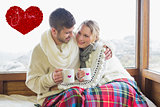 Composite image of loving couple in winter wear with cups against window