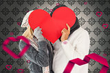 Composite image of couple in winter fashion posing with heart shape