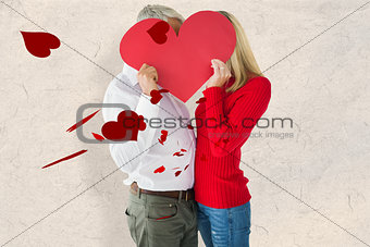 Composite image of couple embracing and holding heart over faces