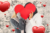 Composite image of couple in winter fashion posing with heart shape