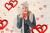 Composite image of smiling woman in winter fashion looking at camera with mug